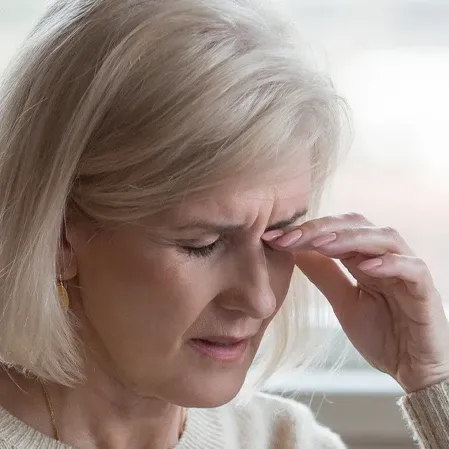 An individual gently touching the eye area, illustrating symptoms commonly associated with dry eyes or eye strain.